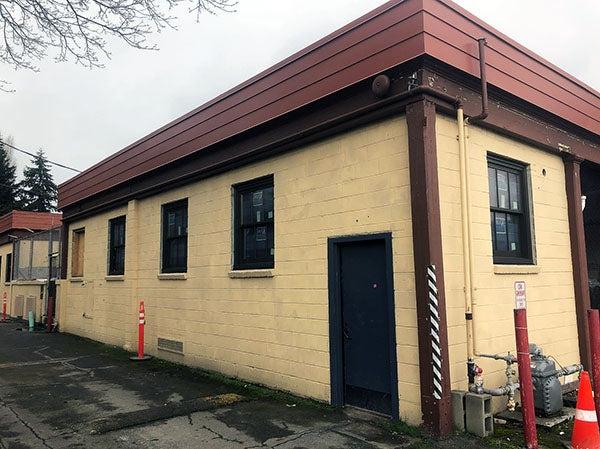 a yellow painted brick building with a rust colored cornice has windows