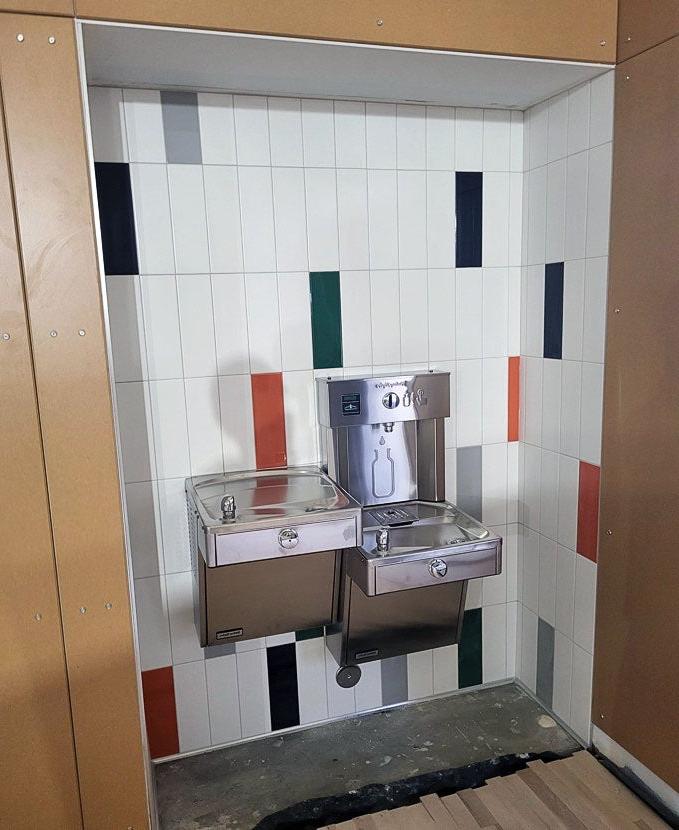 an alcove has tile walls, a drinking fountain, and a water bottle filling station