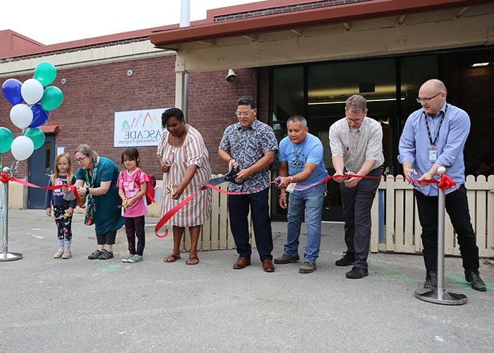 a group of people hold scissors and have just cut a red ribbon